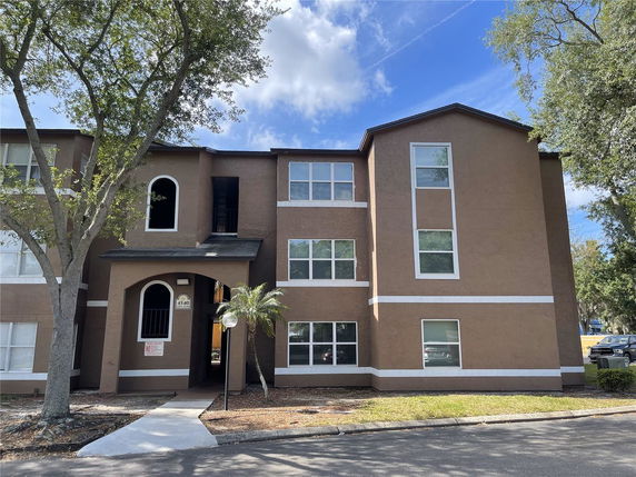 Front view of a multi-story residential building with arched entrance and multiple windows.
