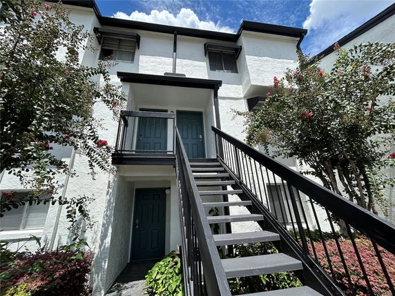 Front view of a multi-story building with exterior stairs leading to an upper entrance.