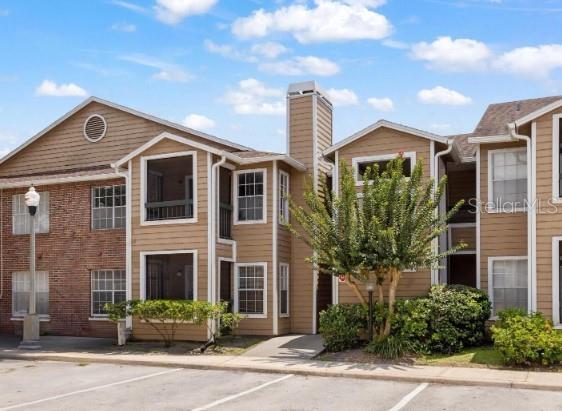 Front view of a multi-story residential building with brick and wood paneling.