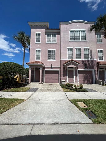Front view of a three-story pink townhouse with double garages.
