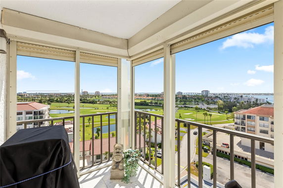 Panoramic view from a building balcony overlooking a golf course and distant buildings.