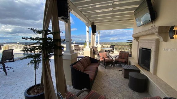Outdoor seating area with patio furniture and fireplace under a pergola, overlooking a scenic view.