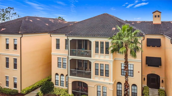 Front view of a multi-story residential building with balconies and a palm tree.