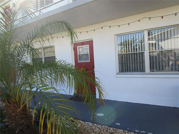 Front view of a building with a red door and large windows.