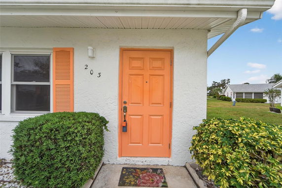 Front view of a house with an orange door and matching window shutter.