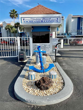 Front view of a condominium entrance with a sign labeled 'Yacht Club Condos'.