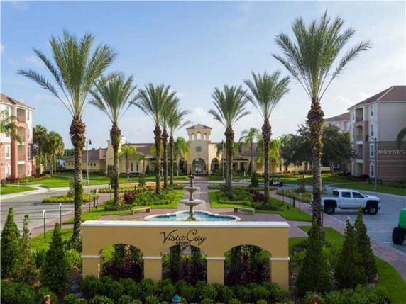 Front view of a resort-style building with palm trees and a fountain.