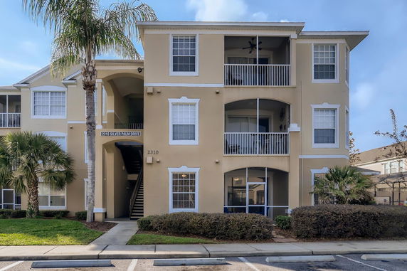 Front view of a three-story apartment building with multiple balconies and a central entrance.