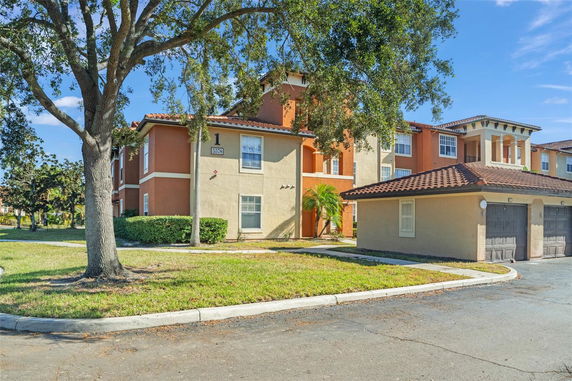 Front view of a multi-story residential building with a tiled roof and attached garages.