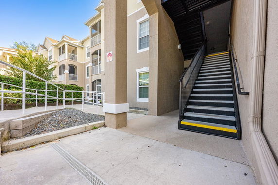 Front view of a multi-story building with balconies and an outdoor staircase.
