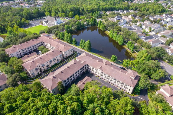 Aerial view of a large residential complex surrounded by trees and nearby a body of water.