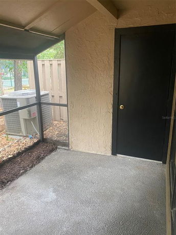 Outdoor area with black door and air conditioning unit visible through screened enclosure.