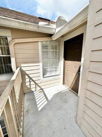 Entryway of a house with beige siding and a brown door