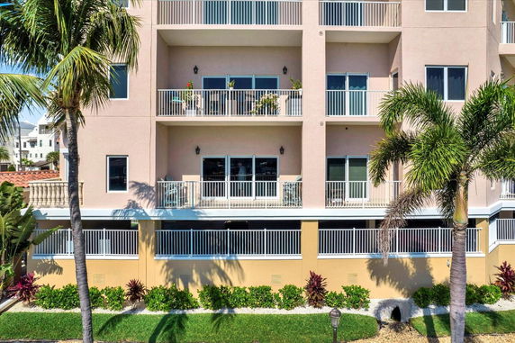 Front view of a multi-story building with balconies and railing.