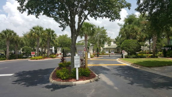 Entrance view with gated access and surrounding greenery.