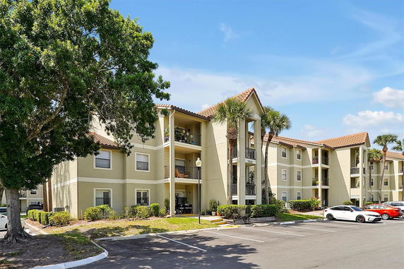 Front view of a three-story apartment building with balconies and tiled roofs.
