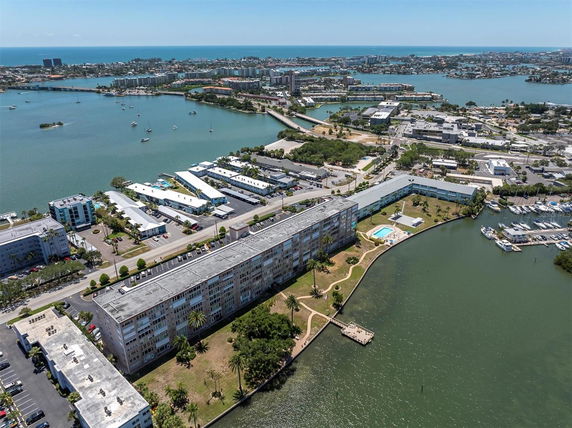 Aerial view of a waterfront residential area with multiple buildings and a swimming pool.