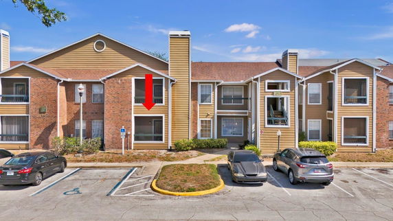 Front view of a multi-story apartment building with parking spaces in front.