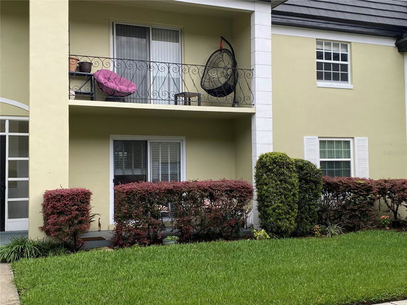 Front view of a two-story house with a balcony and well-maintained shrubs.