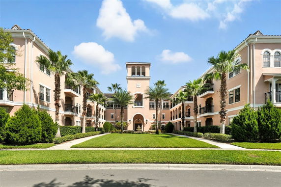 Front view of a multi-story building with a central tower section and palm trees in front.