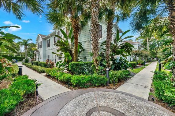 Front view of a two-story house with shutters and lush greenery.