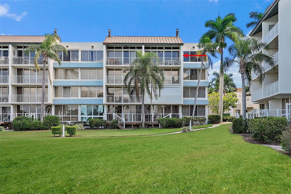 Front view of a multi-story residential building with balconies and palm trees.