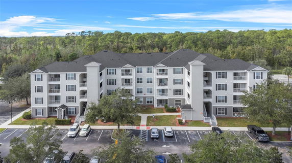 Front view of a multi-story apartment building with parking area in front.