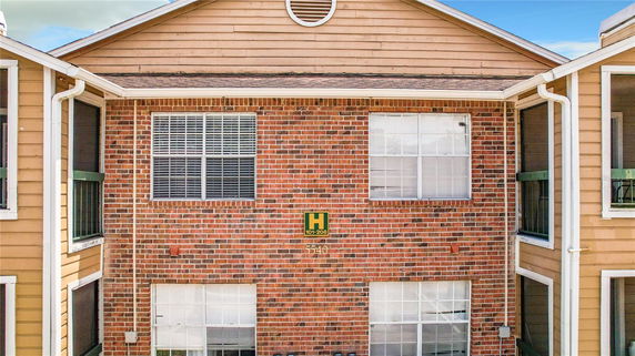 Front view of a brick-clad building with multiple windows and a gabled roof.