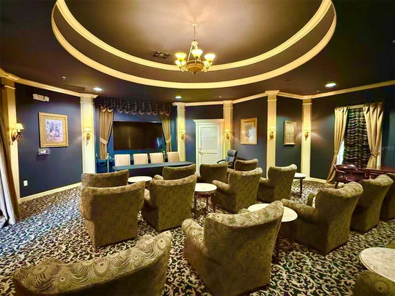 Interior view of a room with multiple chairs and tables arranged facing a large screen.