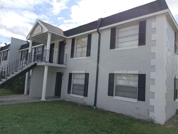 Front view of a two-story residential building with exterior stairs and columns.