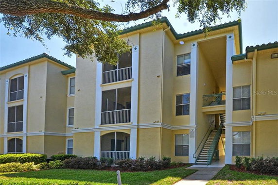Front view of a three-story apartment building with multiple balconies and a central staircase.