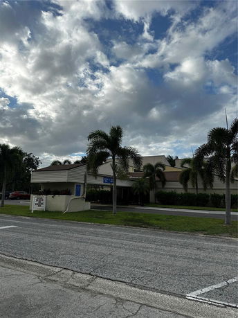 Front view of a building with a covered entrance and palm trees.