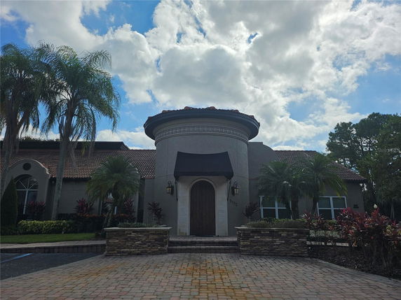 Front view of a house with tile roofing and arched windows.