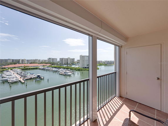 Balcony view overlooking a marina with boats and distant buildings.