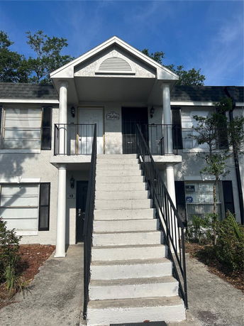 Front view of a two-story house with a central staircase and column-supported entrance.