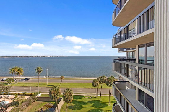 View from a high-rise balcony overlooking a body of water and a coastal road.