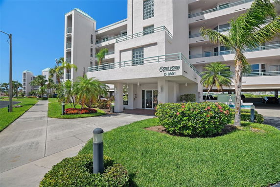 Front view of a multi-story building with balconies and a landscaped entrance.