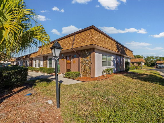 Front view of a single-story building with a brown roof and stone accents.
