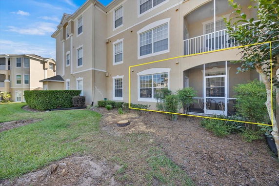 Front view of a multi-story residential building with a highlighted ground floor unit featuring large windows.