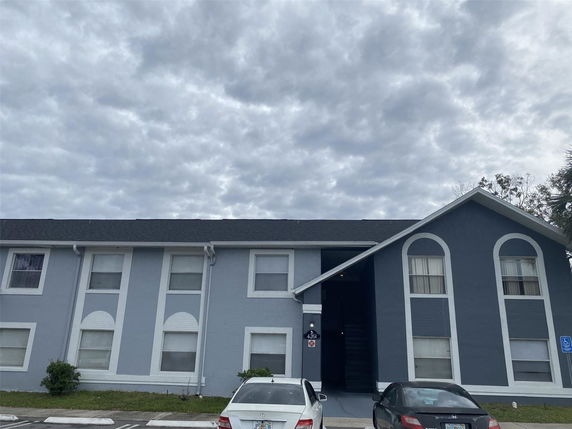 Front view of a two-story building with a dark roof and arched window designs.