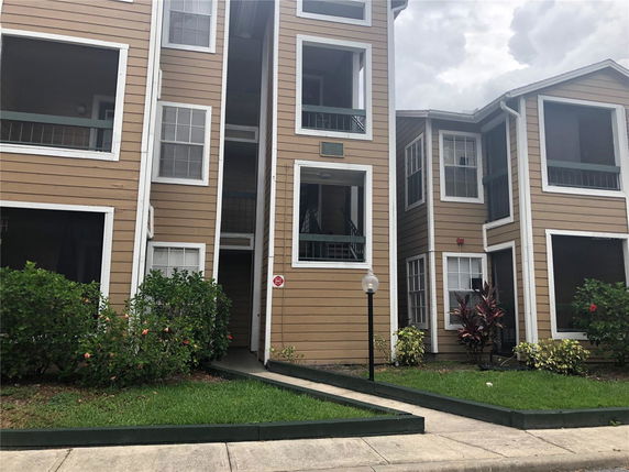 Front view of a multi-story residential building with brown siding and white trim.