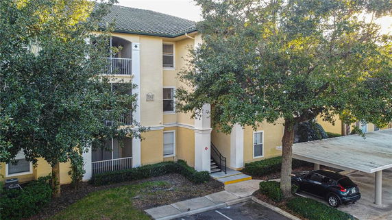 Front view of a multi-story apartment building with balconies and a tiled roof.