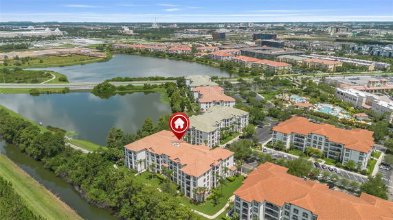 Panoramic view of residential buildings with orange roofs by a lake.