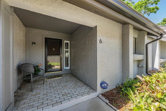 Front view of a house entryway with a brick patio and a chair.