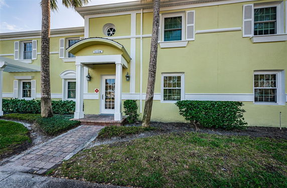 Front view of a yellow two-story house with white trim and a small porch.