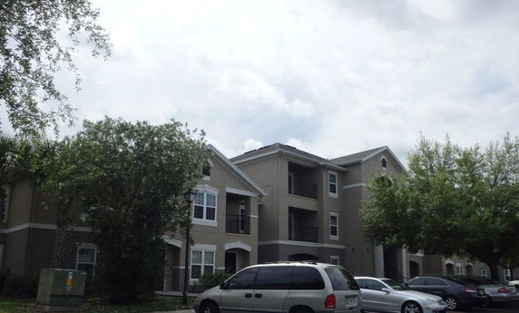 Front view of a multi-story apartment building with balconies and parked cars.