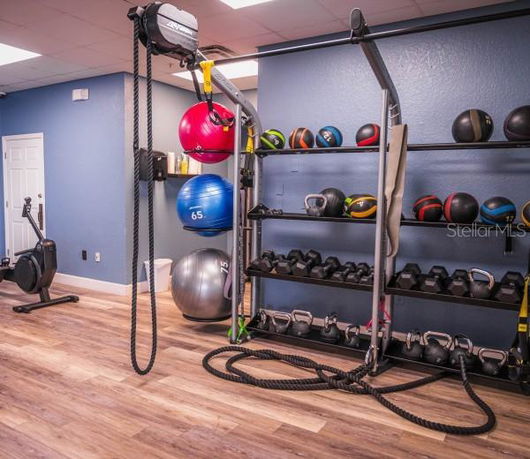 Interior view of a gym area with exercise equipment including dumbbells, kettlebells, and medicine balls.