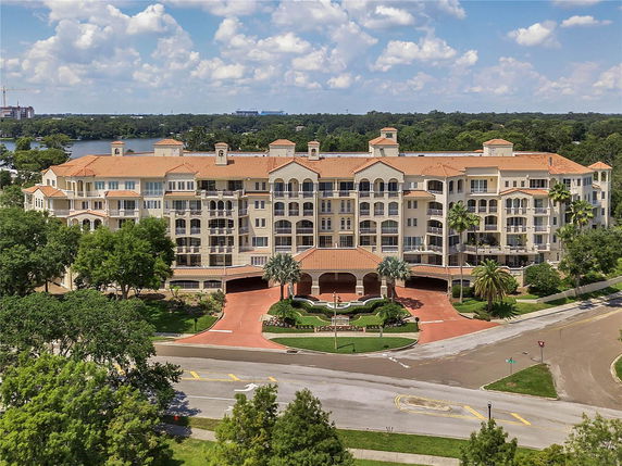 Front view of a large multi-story residential building with balconies and a terracotta roof.