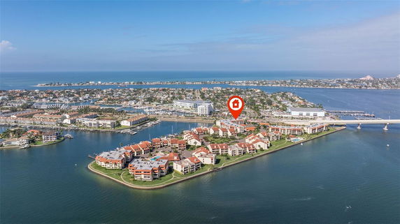 Aerial view of a waterfront residential area with multiple buildings and a bridge.