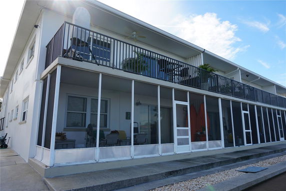 Front view of a two-story building with a screened porch and upper balcony.